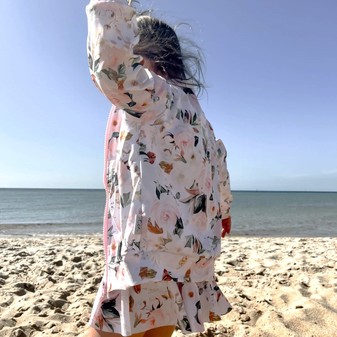 toddler playing in her matching swimming dress and jacket in the sun. The dress has nappy change snaps